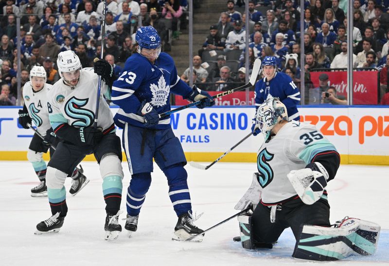 Oct 31, 2024; Toronto, Ontario, CAN;  Seattle Kraken goalie Joey Daccord (35) makes a pad save as defenseman Joshua Mahura (28) covers Toronto Maple Leafs forward Matthew Knies in the third period at Scotiabank Arena. Mandatory Credit: Dan Hamilton-Imagn Images