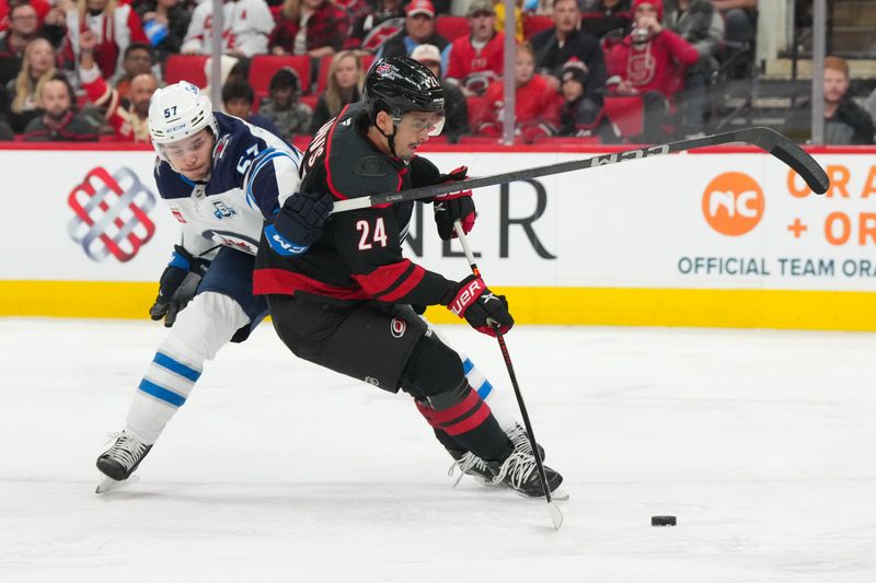Nov 28, 2025; Raleigh, North Carolina, USA;  Carolina Hurricanes center Seth Jarvis (24) cuts to the net past Winnipeg Jets defenseman Elias Salomonsson (57) during the third period at Lenovo Center. Mandatory Credit: James Guillory-Imagn Images