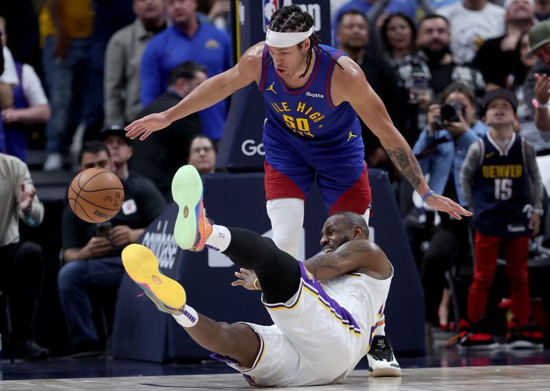 DENVER, COLORADO - APRIL 20: LeBron James #23 of the Los Angeles Lakers falls to the court against Aaron Gordon #50 of the Denver Nuggets in the fourth quarter during game one of the Western Conference First Round Playoffs at Ball Arena on April 20, 2024 in Denver, Colorado.  NOTE TO USER: User expressly acknowledges and agrees that, by downloading and or using this photograph, User is consenting to the terms and conditions of the Getty Images License Agreement. (Photo by Matthew Stockman/Getty Images)