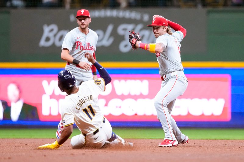 Sep 17, 2024; Milwaukee, Wisconsin, USA;  Philadelphia Phillies second baseman Bryson Stott (5) turns a double play as Milwaukee Brewers left fielder Jackson Chourio (11) slides into second base during the sixth inning at American Family Field. Mandatory Credit: Jeff Hanisch-Imagn Images