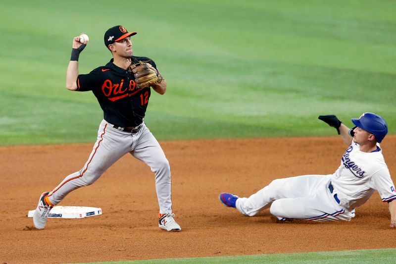 Oct 10, 2023; Arlington, Texas, USA; Texas Rangers shortstop Corey Seager (5) is out at second against Baltimore Orioles second baseman Adam Frazier (12) on a double play in the fourth inning during game three of the ALDS for the 2023 MLB playoffs at Globe Life Field. Mandatory Credit: Andrew Dieb-USA TODAY Sports