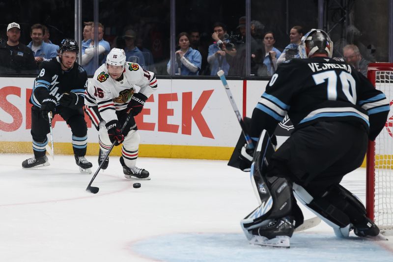 Feb 25, 2025; Salt Lake City, Utah, USA; Chicago Blackhawks center Craig Smith (15) skates against Utah Hockey Club defenseman Mikhail Sergachev (98) and goaltender Karel Vejmelka (70) during the second period at Delta Center. Mandatory Credit: Rob Gray-Imagn Images