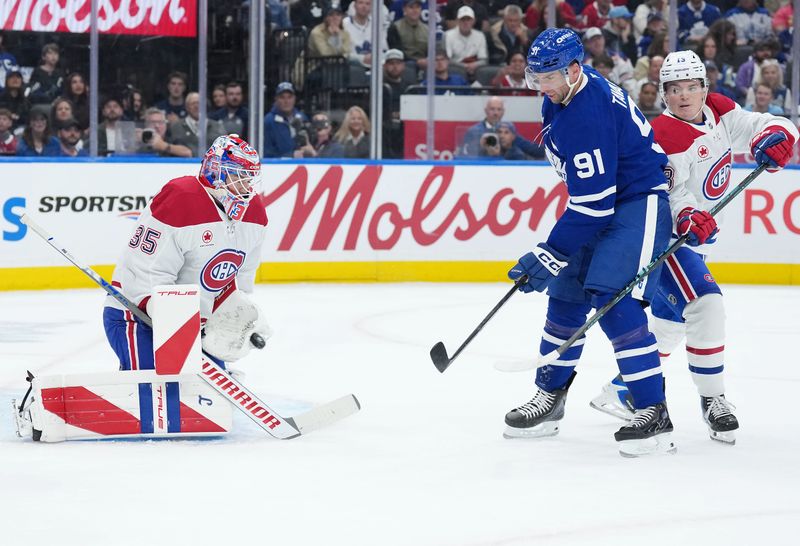 Oct 8, 2025; Toronto, Ontario, CAN;  Toronto Maple Leafs center John Tavares (91) battles for the puck with Montreal Canadiens right wing Cole Caufield (13) during the first period at Scotiabank Arena. Mandatory Credit: Nick Turchiaro-Imagn Images