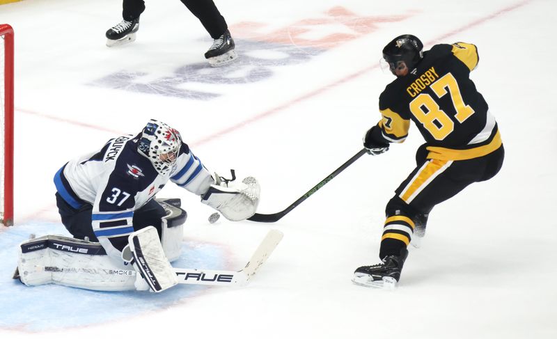 Mar 21, 2026; Pittsburgh, Pennsylvania, USA;  Winnipeg Jets goaltender Connor Hellebuyck (37) makes a save against Pittsburgh Penguins center Sidney Crosby (87) in overtime at PPG Paints Arena. Mandatory Credit: Charles LeClaire-Imagn Images