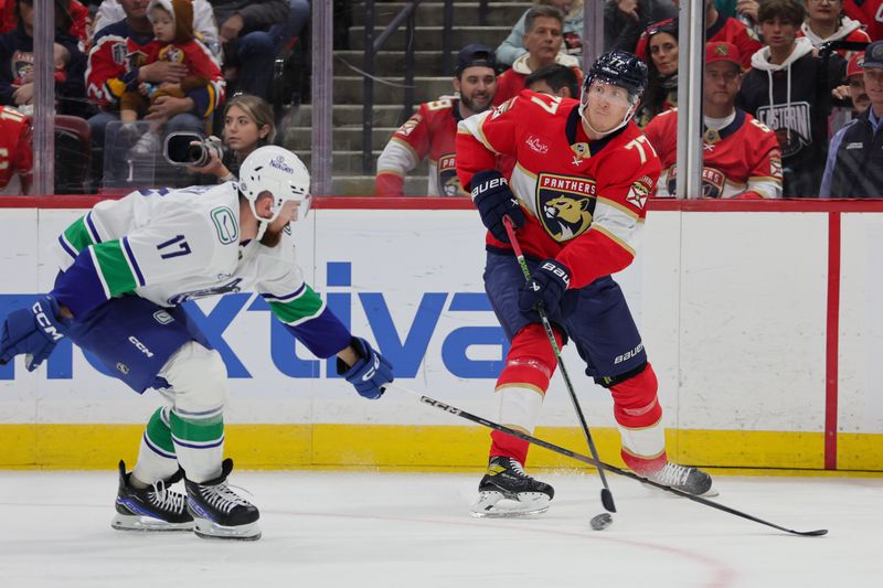 Oct 17, 2024; Sunrise, Florida, USA; Florida Panthers defenseman Niko Mikkola (77) moves the puck as Vancouver Canucks defenseman Filip Hronek (17) defends during the first period at Amerant Bank Arena. Mandatory Credit: Sam Navarro-Imagn Images