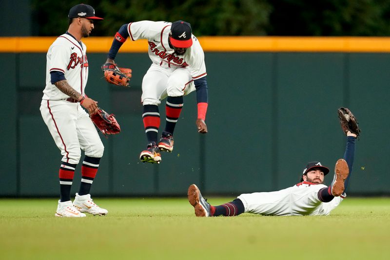 Oct 12, 2022; Atlanta, Georgia, USA; Atlanta Braves shortstop Dansby Swanson (right) makes a catch on a fly ball as center fielder Michael Harris II (middle) leaps over him while left fielder Eddie Rosario (8) supports in the game against the Philadelphia Phillies in the sixth inning during game two of the NLDS for the 2022 MLB Playoffs at Truist Park. Mandatory Credit: Dale Zanine-USA TODAY Sports