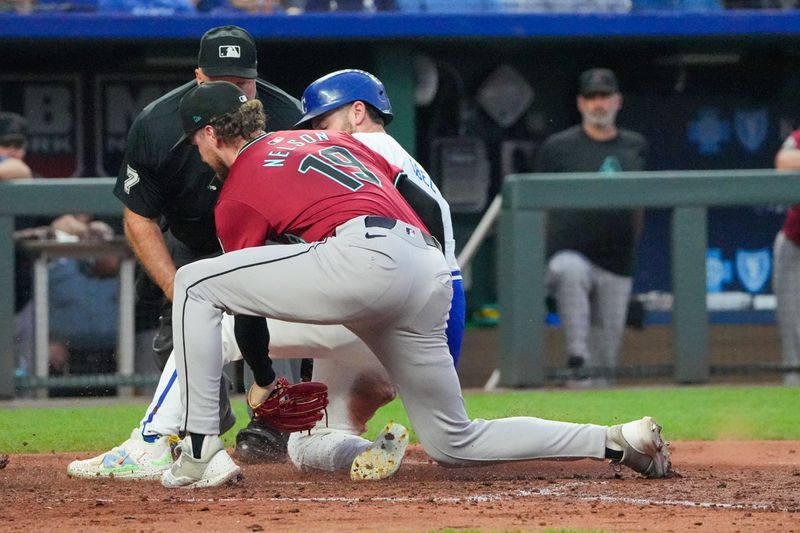 Jul 24, 2024; Kansas City, Missouri, USA; Arizona Diamondbacks pitcher Ryne Nelson (19) misses the tag as Kansas City Royals center fielder Kyle Isbel (28) scores on a wild pitch in the fourth inning at Kauffman Stadium. Mandatory Credit: Denny Medley-USA TODAY Sports