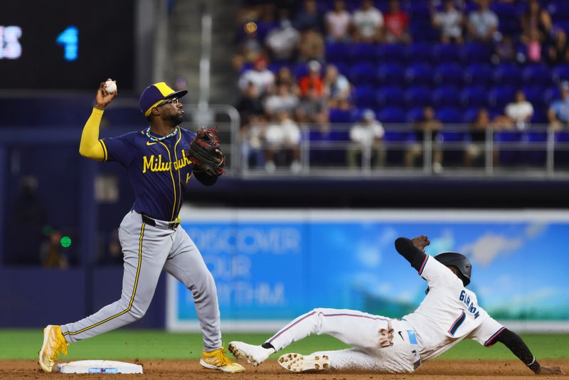 May 20, 2024; Miami, Florida, USA; Milwaukee Brewers second baseman Andruw Monasterio (14) turns a double play as Miami Marlins left fielder Nick Gordon (1) slides at second base during the seventh inning at loanDepot Park. Mandatory Credit: Sam Navarro-USA TODAY Sports