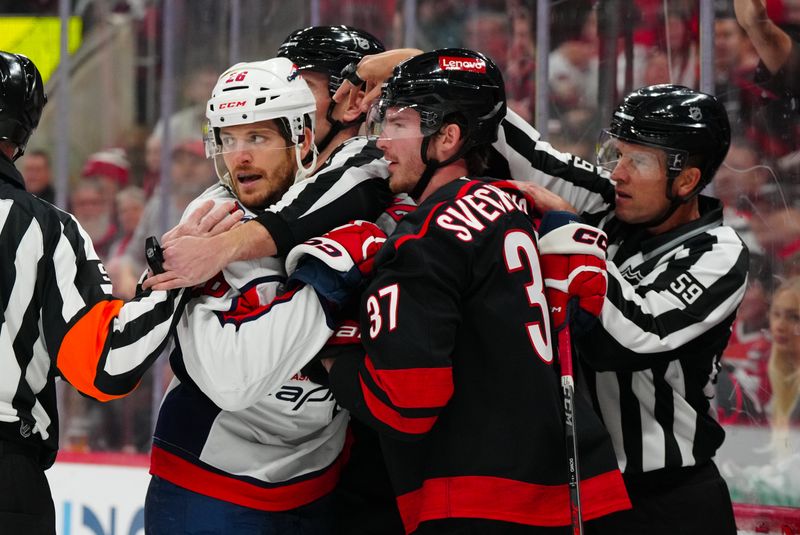 Nov 3, 2024; Raleigh, North Carolina, USA;  Carolina Hurricanes right wing Andrei Svechnikov (37) and Washington Capitals center Nic Dowd (26) grab hold of each other during the first period at Lenovo Center. Mandatory Credit: James Guillory-Imagn Images