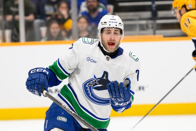 Jan 29, 2025; Nashville, Tennessee, USA;  Vancouver Canucks defenseman Carson Soucy (7) takes a shot to the mouth against the Nashville Predators during the second period at Bridgestone Arena. Mandatory Credit: Steve Roberts-Imagn Images