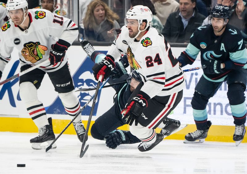 Jan 24, 2024; Seattle, Washington, USA; Chicago Blackhawks defenseman Jaycob Megna (24) is knocked to the ice by Seattle Kraken forward Tomas Tatar (90) during the first period at Climate Pledge Arena. Mandatory Credit: Stephen Brashear-USA TODAY Sports