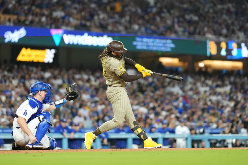 Sep 25, 2024; Los Angeles, California, USA; San Diego Padres right fielder Fernando Tatis Jr. (23) hits a solo home run in the fifth inning as Los Angeles Dodgers catcher Will Smith (16) watches at Dodger Stadium. Mandatory Credit: Kirby Lee-Imagn Images