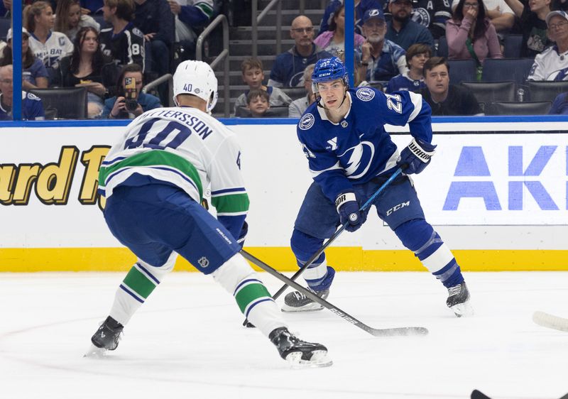 Oct 15, 2024; Tampa, Florida, USA; Tampa Bay Lightning center Brayden Point (21) passes the puck as Vancouver Canucks center Elias Pettersson (40) defends during the first period at Amalie Arena. Mandatory Credit: Kim Klement Neitzel-Imagn Images