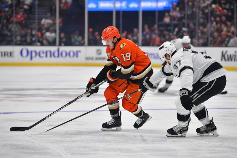 Nov 29, 2024; Anaheim, California, USA; Anaheim Ducks right wing Troy Terry (19) moves the puck against Los Angeles Kings left wing Warren Foegele (37) during the second period at Honda Center. Mandatory Credit: Gary A. Vasquez-Imagn Images