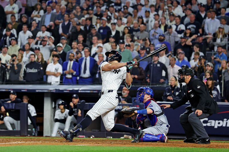 Oct 30, 2024; New York, New York, USA; New York Yankees designated hitter Giancarlo Stanton (27) hits an RBI sacrifice fly during the sixth inning against the Los Angeles Dodgers in game four of the 2024 MLB World Series at Yankee Stadium. Mandatory Credit: Brad Penner-Imagn Images