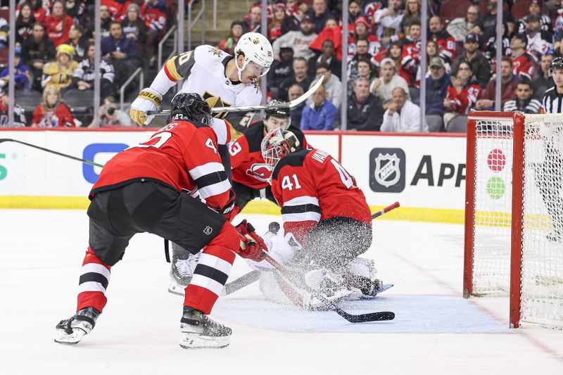 Jan 22, 2024; Newark, New Jersey, USA; New Jersey Devils goaltender Vitek Vanecek (41) makes a save in front of defenseman Luke Hughes (43) and Vegas Golden Knights center Chandler Stephenson (20) during overtime at Prudential Center. Mandatory Credit: Vincent Carchietta-USA TODAY Sports