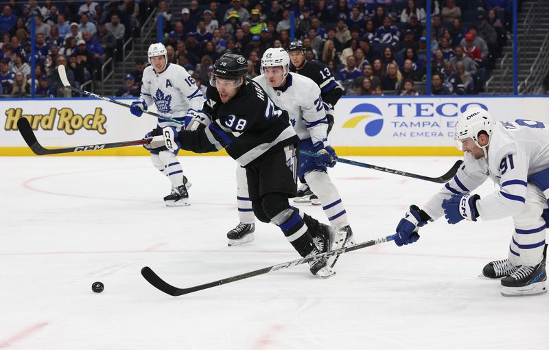 Nov 30, 2024; Tampa, Florida, USA; Tampa Bay Lightning left wing Brandon Hagel (38) skates with the puck as Toronto Maple Leafs center John Tavares (91) and right wing Pontus Holmberg (29) defend during the second period at Amalie Arena. Mandatory Credit: Kim Klement Neitzel-Imagn Images