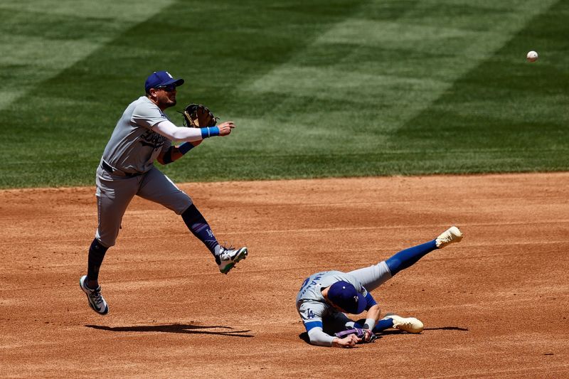 Jun 20, 2024; Denver, Colorado, USA; Los Angeles Dodgers shortstop Miguel Rojas (11) makes a throw to first as third baseman Kike Hernandez (8) slides on the infield in the first inning against the Colorado Rockies at Coors Field. Mandatory Credit: Isaiah J. Downing-USA TODAY Sports