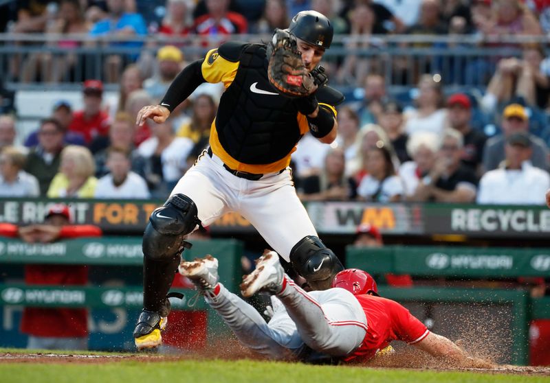 Aug 23, 2024; Pittsburgh, Pennsylvania, USA;  Cincinnati Reds left fielder Spencer Steer (right) slides home to score a run on a suicide squeeze past the tag attempt of Pittsburgh Pirates catcher Joey Bart (14) during the fourth inning at PNC Park. Mandatory Credit: Charles LeClaire-USA TODAY Sports