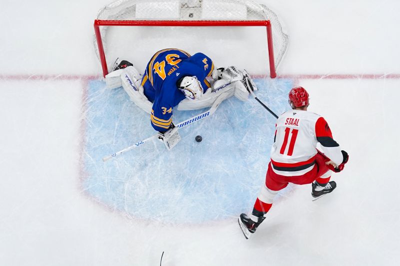 Nov 8, 2025; Raleigh, North Carolina, USA;  Buffalo Sabres goaltender Alex Lyon (34) stops the scoring attempt by Carolina Hurricanes center Jordan Staal (11) during the second period at Lenovo Center. Mandatory Credit: James Guillory-Imagn Images