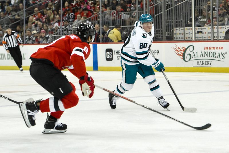 Nov 10, 2024; Newark, New Jersey, USA; San Jose Sharks left wing Fabian Zetterlund (20) passes the puck against New Jersey Devils defenseman Johnathan Kovacevic (8) during the first period at Prudential Center. Mandatory Credit: John Jones-Imagn Images