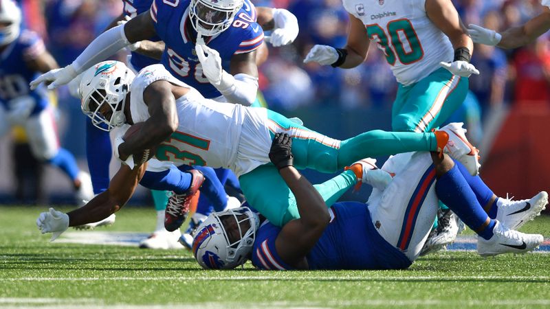 Miami Dolphins running back Raheem Mostert (31) is brought down by Buffalo Bills defensive tackle Ed Oliver, bottom, in front of Bills defensive end Shaq Lawson (90) during the second half an NFL football game, Sunday, Oct. 1, 2023, in Orchard Park, N.Y. (AP Photo/Adrian Kraus)