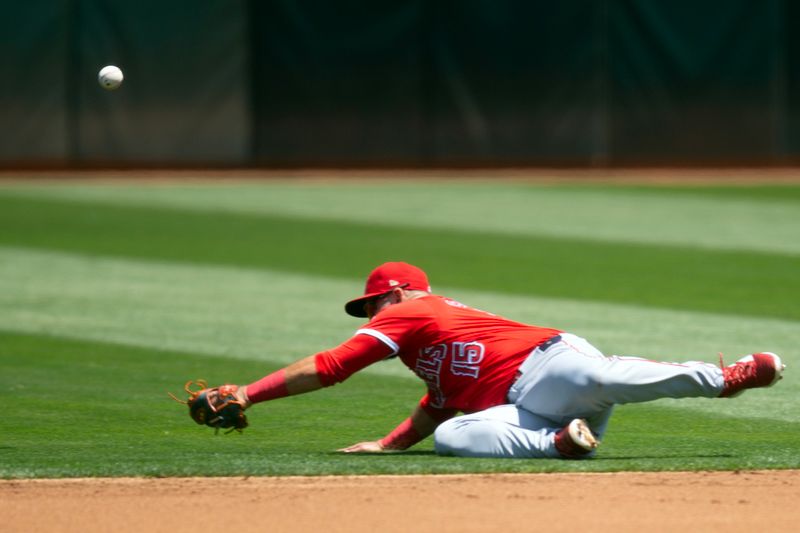 Jul 20, 2024; Oakland, California, USA; Los Angeles Angels second baseman Luis Guillorme (15) dives in vain for a single by Oakland Athletics left fielder Miguel Andujar during the first inning at Oakland-Alameda County Coliseum. Mandatory Credit: D. Ross Cameron-USA TODAY Sports