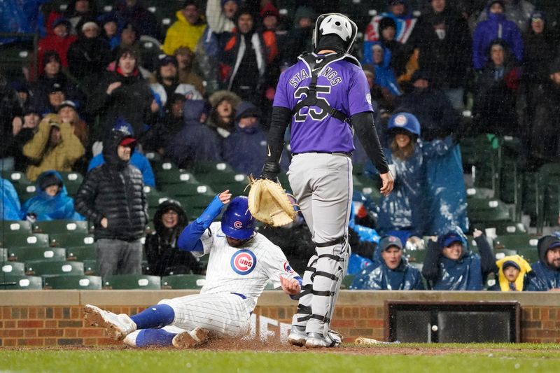 Apr 3, 2024; Chicago, Illinois, USA; Chicago Cubs center fielder Mike Tauchman (40) scores as Colorado Rockies catcher Jacob Stallings (25) stands nearby during the sixth inning at Wrigley Field. Mandatory Credit: David Banks-USA TODAY Sports