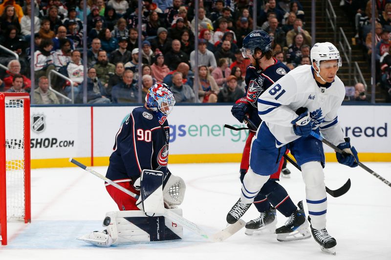 Oct 29, 2025; Columbus, Ohio, USA; Columbus Blue Jackets goalie Elvis Merzlikins (90) makes a pad save as Toronto Maple Leafs center Dakota Joshua (81) looks for a rebound during the first period at Nationwide Arena. Mandatory Credit: Russell LaBounty-Imagn Images