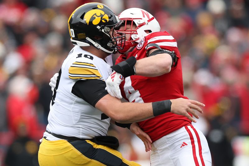 Nov 24, 2023; Lincoln, Nebraska, USA; Iowa Hawkeyes quarterback Deacon Hill (10) is pressured by Nebraska Cornhuskers linebacker Luke Reimer (4) at Memorial Stadium. Mandatory Credit: Reese Strickland-USA TODAY Sports