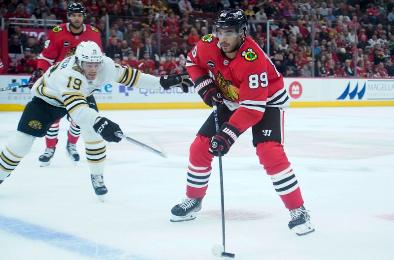 Oct 24, 2023; Chicago, Illinois, USA; Boston Bruins center Johnny Beecher (19) defends Chicago Blackhawks center Andreas Athanasiou (89) during the first period against the Boston Bruins at United Center. Mandatory Credit: David Banks-USA TODAY Sports