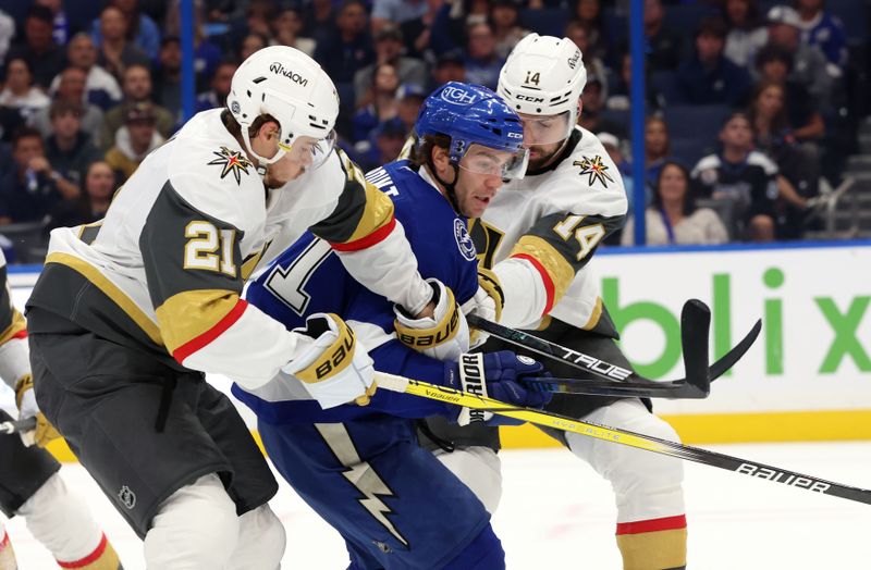 Oct 17, 2024; Tampa, Florida, USA; Vegas Golden Knights defenseman Zach Whitecloud (2)1 and defenseman Nicolas Hague (14) defends Tampa Bay Lightning center Brayden Point (21) during the first period at Amalie Arena. Mandatory Credit: Kim Klement Neitzel-Imagn Images