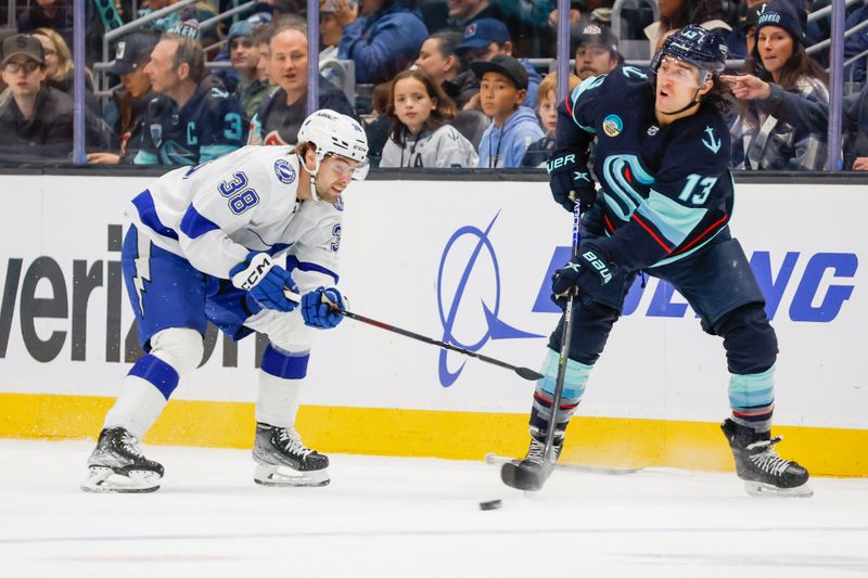 Dec 9, 2023; Seattle, Washington, USA; Seattle Kraken left wing Brandon Tanev (13) passes the puck away from Tampa Bay Lightning left wing Brandon Hagel (38) during the first period at Climate Pledge Arena. Mandatory Credit: Joe Nicholson-USA TODAY Sports