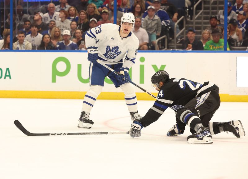 Apr 17, 2024; Tampa, Florida, USA; Toronto Maple Leafs left wing Matthew Knies (23) passes the puck as Tampa Bay Lightning defenseman Matt Dumba (24) defends during the second period at Amalie Arena. Mandatory Credit: Kim Klement Neitzel-USA TODAY Sports