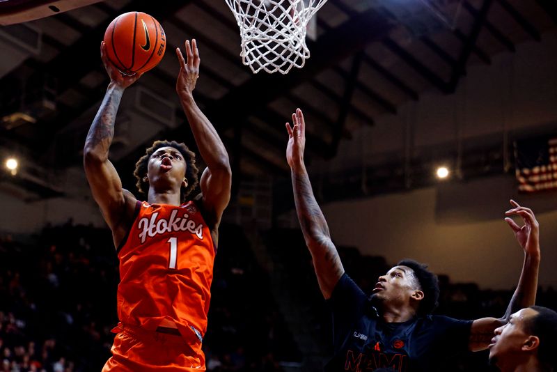 Jan 4, 2025; Blacksburg, Virginia, USA; Virginia Tech Hokies forward Tobi Lawal (1) shoots the ball against Miami Hurricanes forward Brandon Johnson (2) during the first half at Cassell Coliseum. Mandatory Credit: Peter Casey-Imagn Images