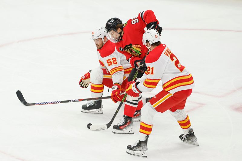 Mar 26, 2024; Chicago, Illinois, USA; Chicago Blackhawks center Connor Bedard (98) battles for the puck with Calgary Flames defenseman MacKenzie Weegar (52) during the first period at United Center. Mandatory Credit: Kamil Krzaczynski-USA TODAY Sports