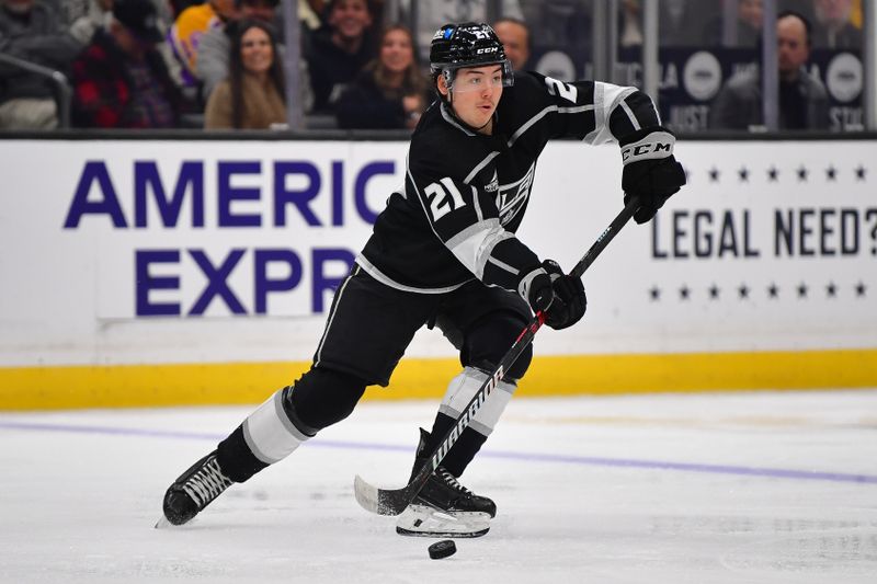 Dec 30, 2023; Los Angeles, California, USA; Los Angeles Kings defenseman Jordan Spence (21) controls the puck against the Edmonton Oilers during the second period at Crypto.com Arena. Mandatory Credit: Gary A. Vasquez-USA TODAY Sports