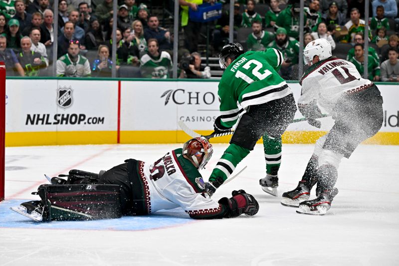 Nov 14, 2023; Dallas, Texas, USA; Dallas Stars center Radek Faksa (12) is hooked by Arizona Coyotes defenseman Juuso Valimaki (4) as Faksa attempts a shot on goaltender Karel Vejmelka (70) during the second period at the American Airlines Center. Mandatory Credit: Jerome Miron-USA TODAY Sports