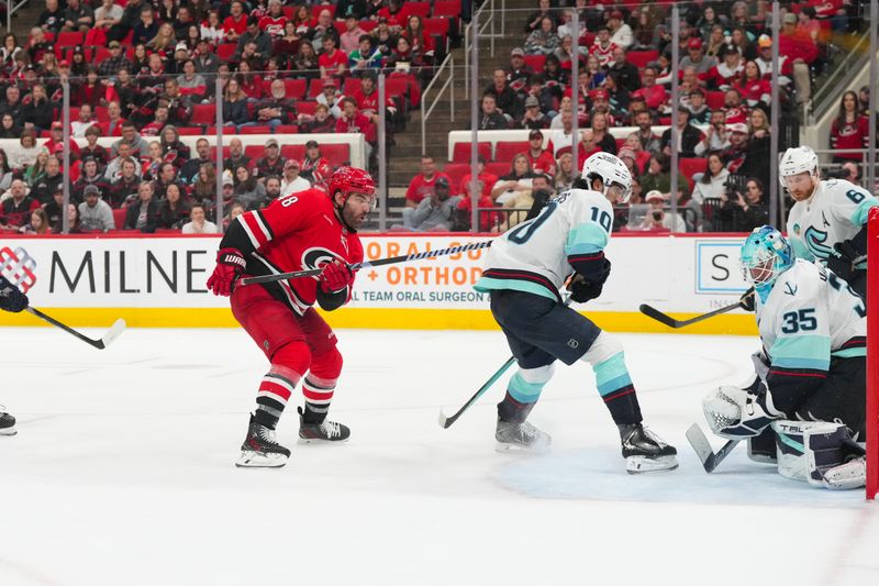 Jan 10, 2026; Raleigh, North Carolina, USA;  Carolina Hurricanes left wing Jordan Martinook (48) watches his goal past Seattle Kraken goaltender Joey Daccord (35) and center Matty Beniers (10) during the third period at Lenovo Center. Mandatory Credit: James Guillory-Imagn Images