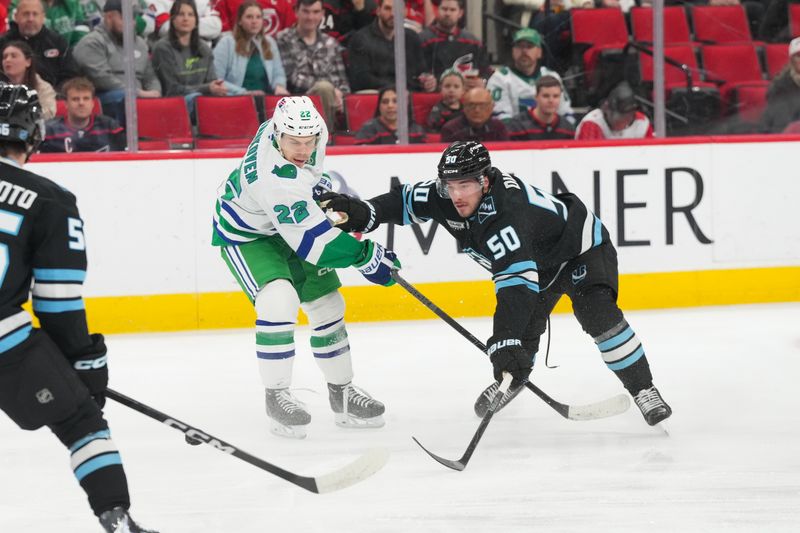 Jan 29, 2026; Raleigh, North Carolina, USA;  Utah Mammoth defenseman Sean Durzi (50) pokes the pcuki away from Carolina Hurricanes center Logan Stankoven (22) during the first period at Lenovo Center. Mandatory Credit: James Guillory-Imagn Images