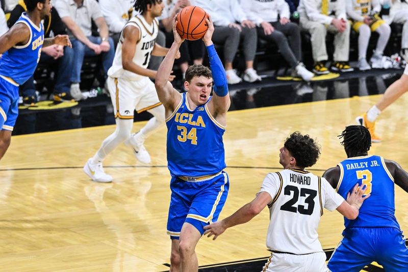 Jan 3, 2026; Iowa City, Iowa, USA; UCLA Bruins forward Tyler Bilodeau (34) grabs a rebound over Iowa Hawkeyes guard Isaia Howard (23) during the second half at Carver-Hawkeye Arena. Mandatory Credit: Jeffrey Becker-Imagn Images