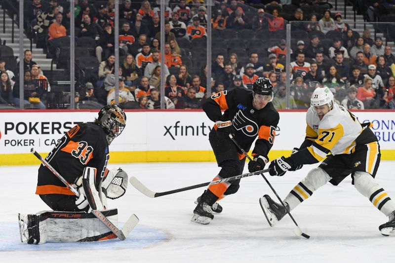 Feb 25, 2025; Philadelphia, Pennsylvania, USA; Philadelphia Flyers defenseman Egor Zamula (5) clears the puck away from Pittsburgh Penguins center Evgeni Malkin (71) in front of goaltender Samuel Ersson (33) during the first period at Wells Fargo Center. Mandatory Credit: Eric Hartline-Imagn Images