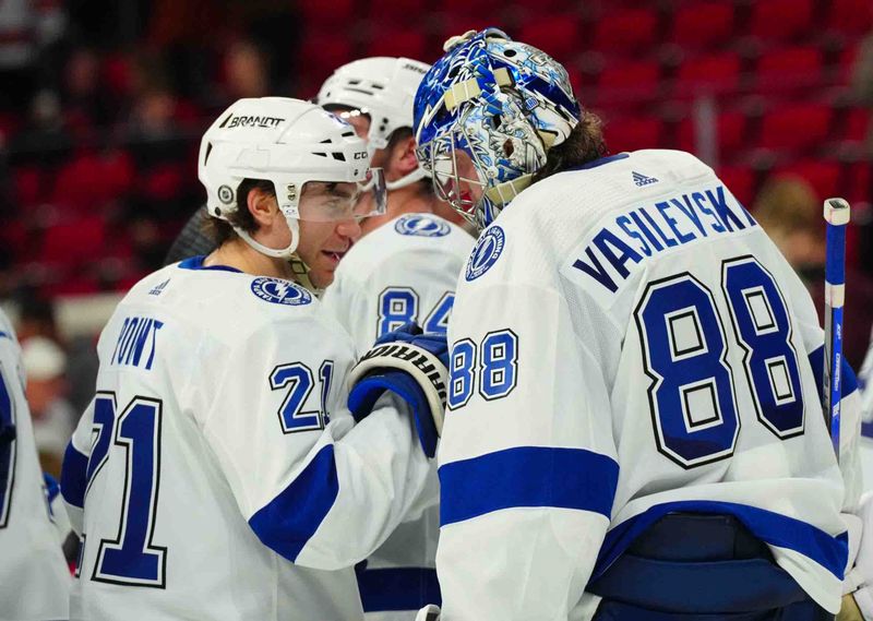 Nov 24, 2023; Raleigh, North Carolina, USA; Tampa Bay Lightning center Brayden Point (21) and  goaltender Andrei Vasilevskiy (88) celebrate their victory against the Carolina Hurricanes at PNC Arena. Mandatory Credit: James Guillory-USA TODAY Sports