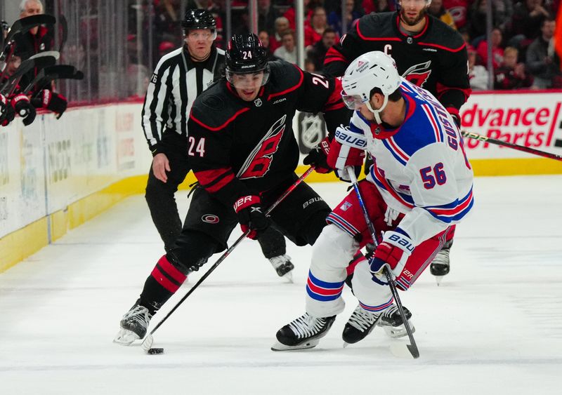 Mar 12, 2024; Raleigh, North Carolina, USA; Carolina Hurricanes center Seth Jarvis (24) tries to skate with the puck past New York Rangers defenseman Erik Gustafsson (56) during the first period at PNC Arena. Mandatory Credit: James Guillory-USA TODAY Sports