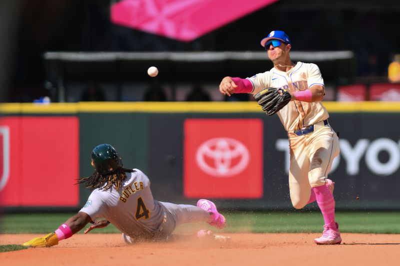 May 12, 2024; Seattle, Washington, USA; Seattle Mariners shortstop Dylan Moore (25) throws over Oakland Athletics right fielder Lawrence Butler (4) to complete the double during the ninth inning at T-Mobile Park. Mandatory Credit: Steven Bisig-USA TODAY Sports