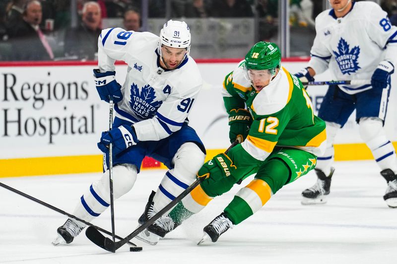 Nov 3, 2024; Saint Paul, Minnesota, USA; Toronto Maple Leafs center John Tavares (91) protects the puck from Minnesota Wild left wing Matt Boldy (12) during the first period at Xcel Energy Center. Mandatory Credit: Brace Hemmelgarn-Imagn Images