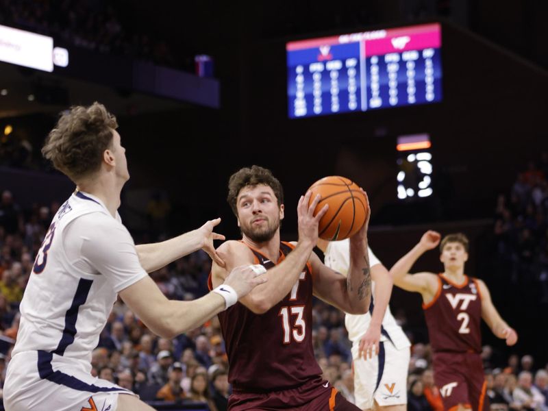 Feb 1, 2025; Charlottesville, Virginia, USA; Virginia Tech Hokies forward Ben Burnham (13) controls the ball as Virginia Cavaliers forward TJ Power (23) defends during the first half at John Paul Jones Arena. Mandatory Credit: Amber Searls-Imagn Images