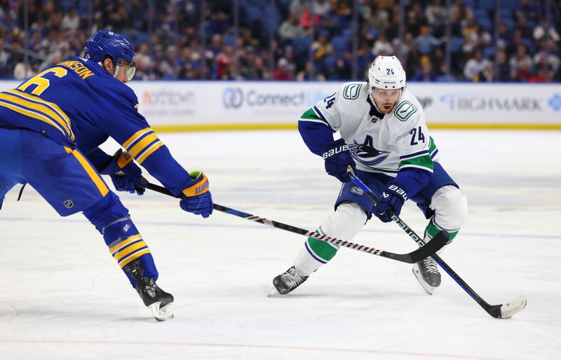 Jan 13, 2024; Buffalo, New York, USA;  Vancouver Canucks center Pius Suter (24) skates up ice with the puck as Buffalo Sabres defenseman Erik Johnson (6) defends during the third period at KeyBank Center. Mandatory Credit: Timothy T. Ludwig-USA TODAY Sports