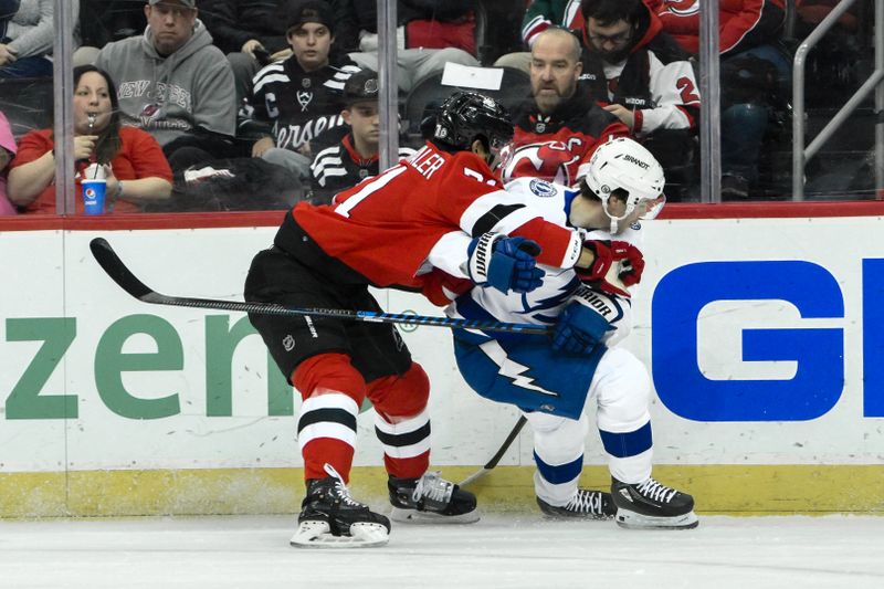 Feb 25, 2024; Newark, New Jersey, USA; Tampa Bay Lightning center Brayden Point (21) skates with the puck while being defended by New Jersey Devils defenseman Jonas Siegenthaler (71) during the first period at Prudential Center. Mandatory Credit: John Jones-USA TODAY Sports