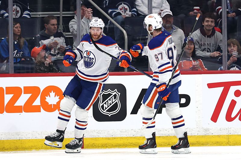 Apr 13, 2025; Winnipeg, Manitoba, CAN; Edmonton Oilers right wing Connor Brown (28) celebrates a goal against the Winnipeg Jets with Edmonton Oilers center Connor McDavid (97) in the second period at Canada Life Centre. Mandatory Credit: James Carey Lauder-Imagn Images